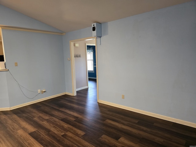 empty room featuring dark wood-type flooring, baseboards, and lofted ceiling