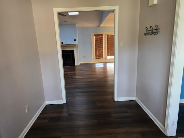 hallway featuring baseboards and dark wood-type flooring