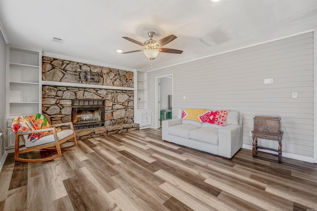 living area with visible vents, built in features, a ceiling fan, and wood finished floors