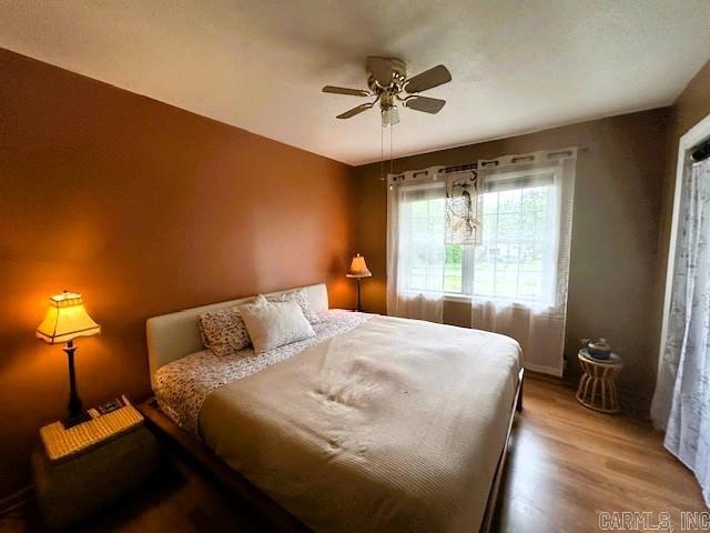 bedroom with wood finished floors, ceiling fan, and baseboards