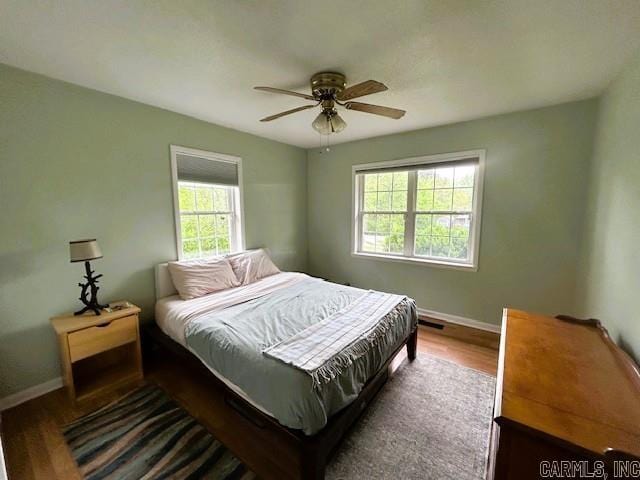 bedroom featuring visible vents, a ceiling fan, dark wood finished floors, and baseboards