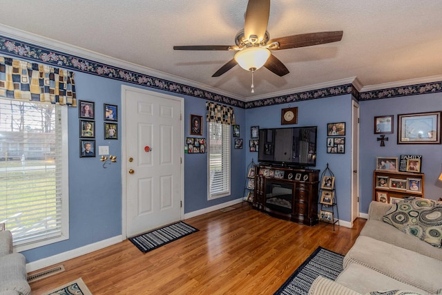 living room featuring a wealth of natural light, ornamental molding, ceiling fan, and wood finished floors