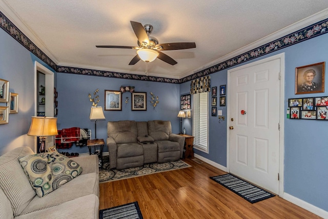 living room with baseboards, crown molding, a ceiling fan, and wood finished floors