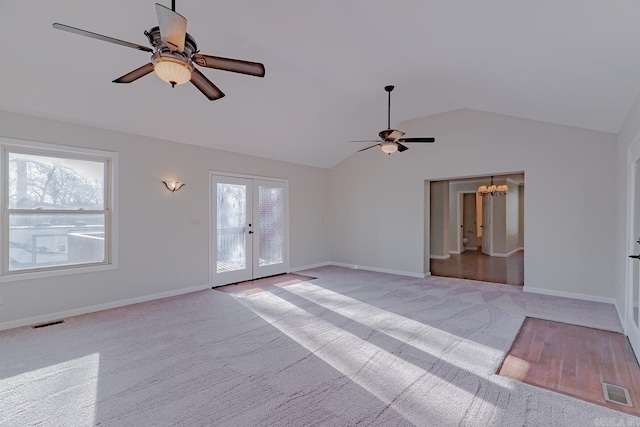 unfurnished living room featuring visible vents, lofted ceiling, a healthy amount of sunlight, and ceiling fan with notable chandelier