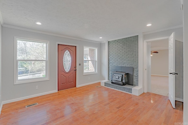 foyer featuring crown molding, a wood stove, and visible vents