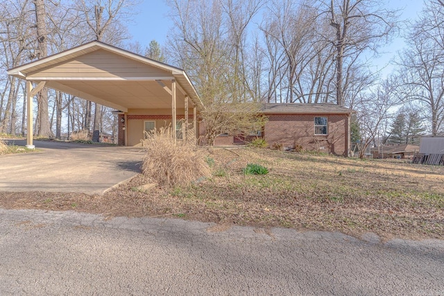 exterior space featuring an attached carport, brick siding, and driveway