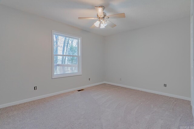 spare room with baseboards, a ceiling fan, visible vents, and light carpet