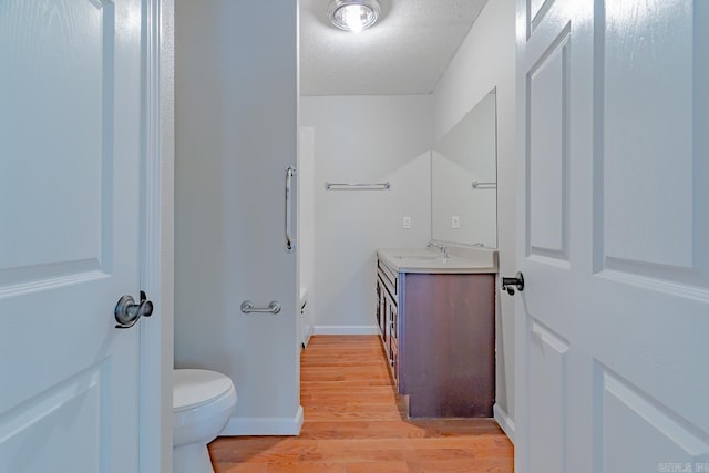 bathroom featuring vanity, wood finished floors, baseboards, a textured ceiling, and toilet