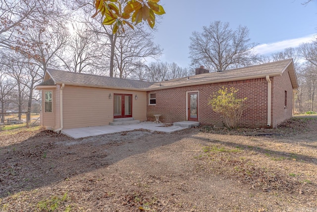 back of house with a chimney, entry steps, french doors, a patio area, and brick siding
