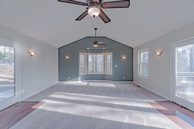 unfurnished living room featuring vaulted ceiling, plenty of natural light, a ceiling fan, and baseboards
