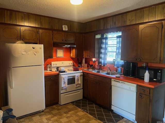 kitchen with a sink, white appliances, light countertops, a textured ceiling, and under cabinet range hood