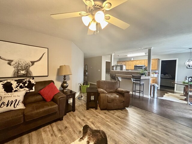 living area featuring baseboards, wood finished floors, a ceiling fan, and vaulted ceiling