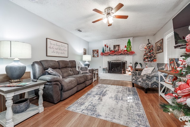 2304 Forrest Park Dr, Arkadelphia, AR 71923 - living room with visible vents, ceiling fan, a fireplace, wood finished floors, and a textured ceiling