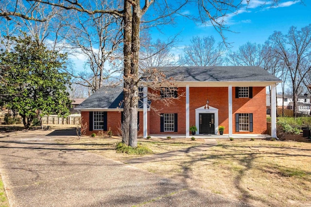 neoclassical / greek revival house with covered porch, brick siding, and driveway