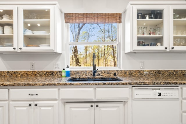 kitchen featuring a sink, dark stone counters, white cabinets, glass insert cabinets, and dishwasher