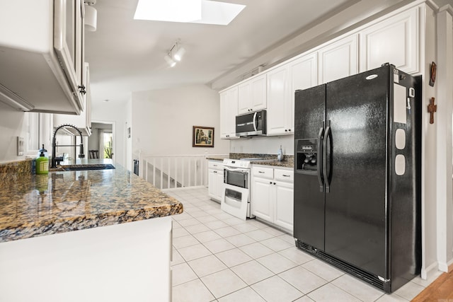 kitchen with stainless steel microwave, white gas range oven, black fridge, white cabinets, and a sink
