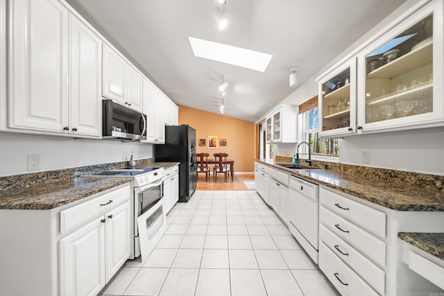 kitchen with a sink, white appliances, white cabinets, light tile patterned flooring, and glass insert cabinets