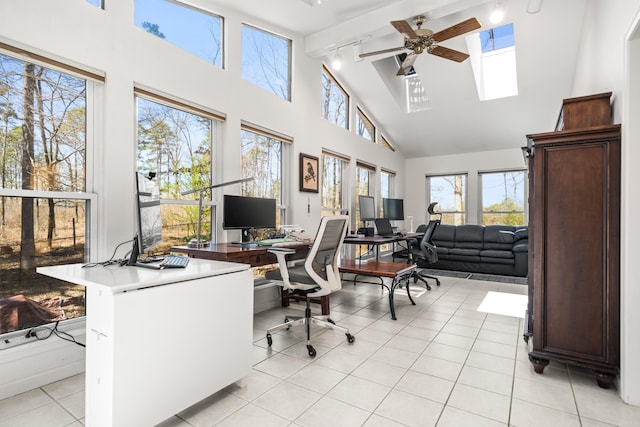 home office featuring high vaulted ceiling, a skylight, rail lighting, light tile patterned floors, and ceiling fan