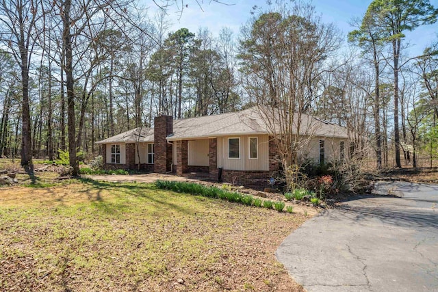 ranch-style home with brick siding, a chimney, and a front yard