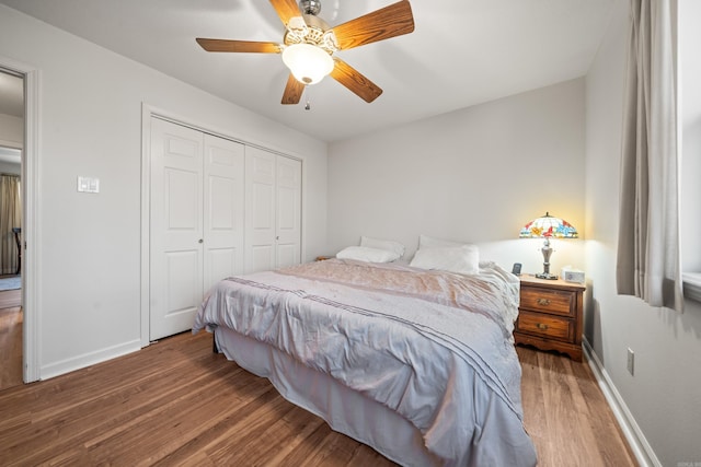 bedroom featuring a ceiling fan, wood finished floors, a closet, and baseboards