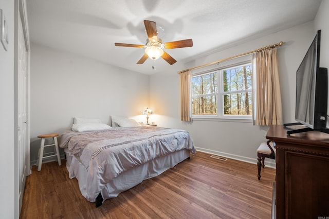 bedroom featuring visible vents, ceiling fan, baseboards, and wood finished floors