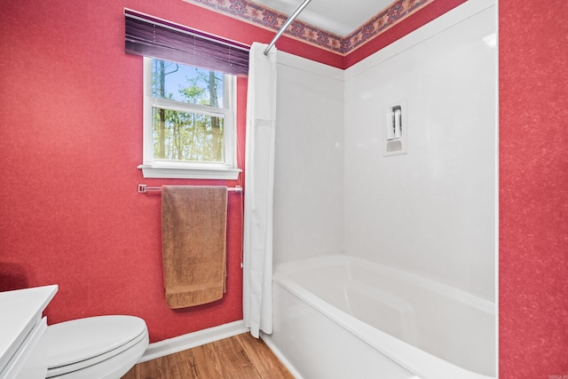 bathroom with toilet, wood finished floors, shower / bathing tub combination, baseboards, and vanity