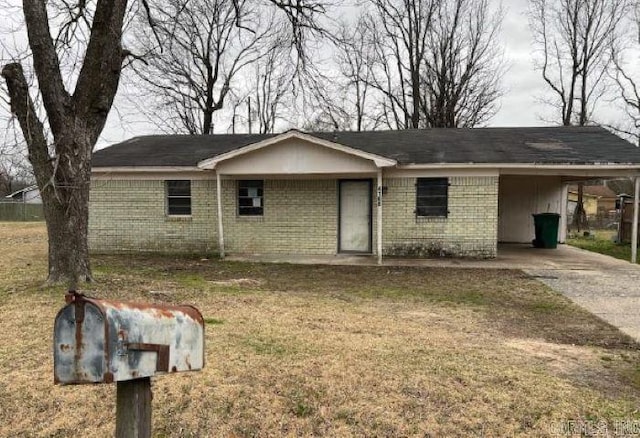 ranch-style home with driveway, an attached carport, brick siding, and a front yard