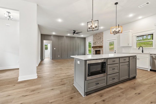 kitchen featuring built in microwave, a chandelier, recessed lighting, gray cabinetry, and open floor plan