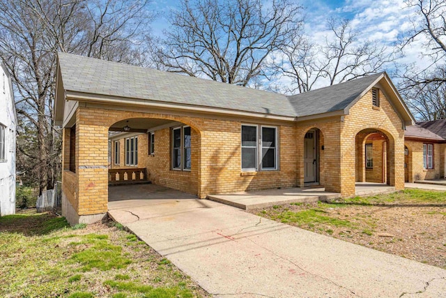 view of front of property with brick siding, an attached carport, driveway, and a shingled roof