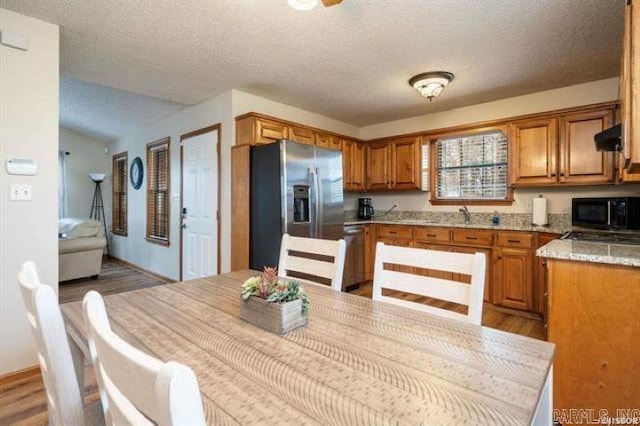 103 River Bend Rd, Hot Springs, AR 71913 - kitchen featuring brown cabinets, light wood finished floors, ventilation hood, black microwave, and stainless steel fridge with ice dispenser