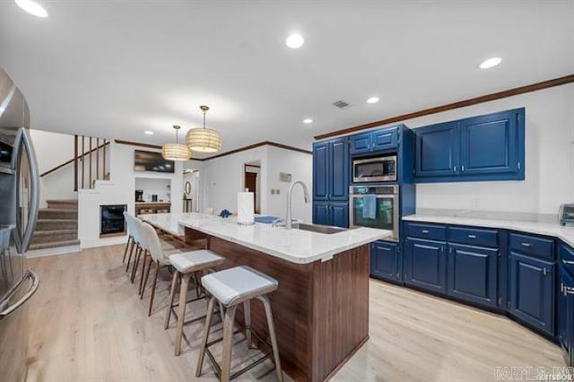 103 River Bend Rd, Hot Springs, AR 71913 - kitchen with a breakfast bar area, light wood finished floors, blue cabinetry, a sink, and appliances with stainless steel finishes