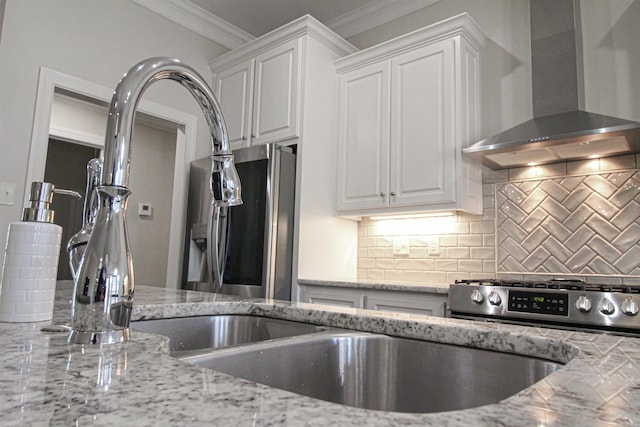 kitchen with backsplash, ornamental molding, white cabinets, and wall chimney range hood