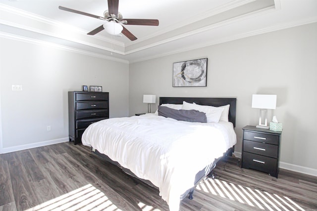 bedroom featuring baseboards, a raised ceiling, wood finished floors, and ornamental molding