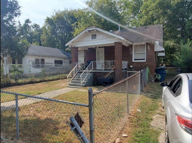 bungalow-style home featuring brick siding, a porch, fence private yard, and a front yard