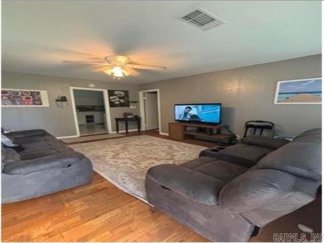 living room featuring visible vents, ceiling fan, and wood finished floors