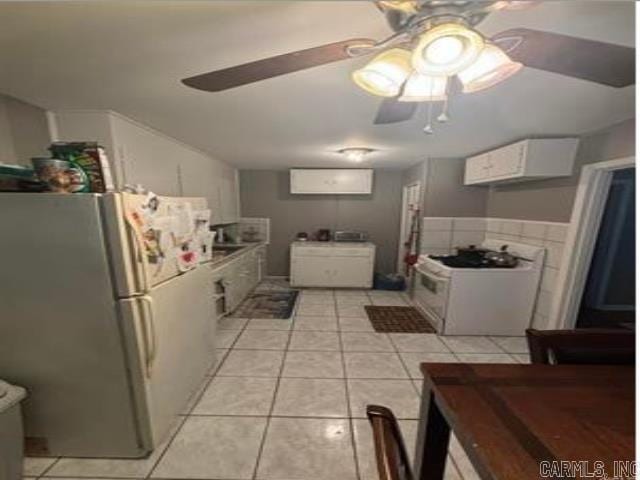 kitchen featuring light tile patterned floors, freestanding refrigerator, and a ceiling fan