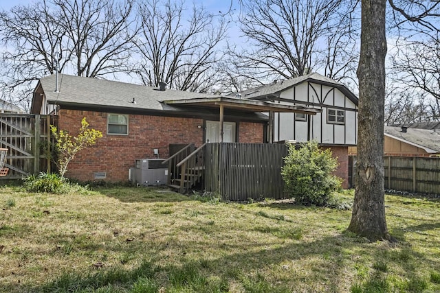 back of property with brick siding, crawl space, a yard, and fence