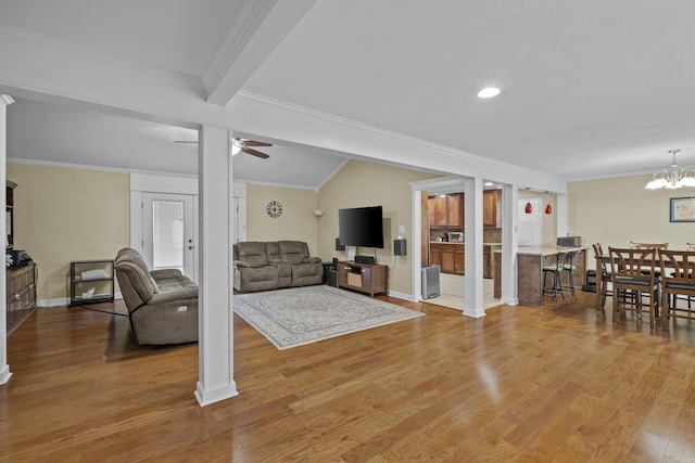 living area featuring baseboards, wood finished floors, crown molding, and ceiling fan with notable chandelier