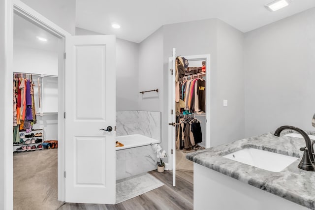 full bath featuring a spacious closet, visible vents, a bath, and wood finished floors