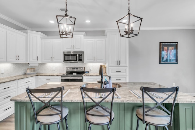 kitchen featuring stainless steel appliances, tasteful backsplash, an inviting chandelier, and a kitchen island with sink