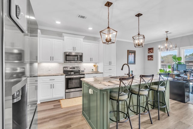 kitchen with a sink, backsplash, appliances with stainless steel finishes, an inviting chandelier, and crown molding