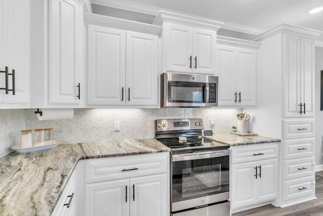 kitchen with white cabinets, light stone countertops, tasteful backsplash, and appliances with stainless steel finishes