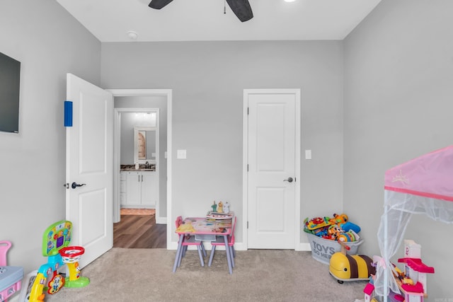 recreation room with a sink, baseboards, carpet, and ceiling fan