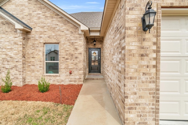 property entrance featuring brick siding, an attached garage, and a shingled roof
