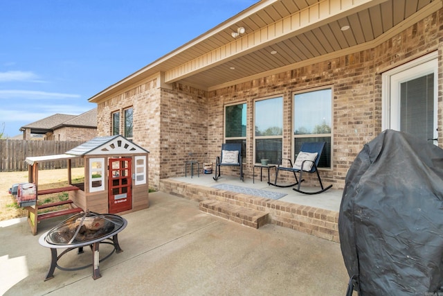 view of patio with grilling area, a fire pit, and fence