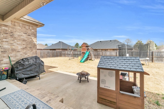 view of patio / terrace featuring a fire pit, a playground, a trampoline, a fenced backyard, and area for grilling