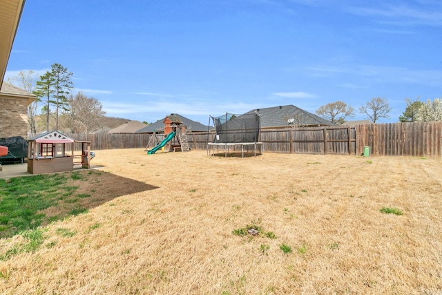 view of yard with a fenced backyard, a playground, and a trampoline