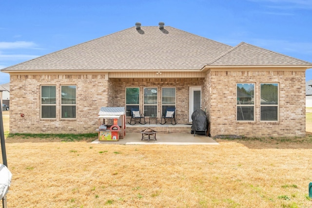 back of house featuring a patio, a lawn, brick siding, and roof with shingles