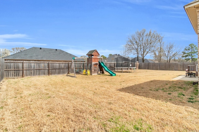view of yard featuring a playground, a trampoline, a fenced backyard, and an outdoor fire pit