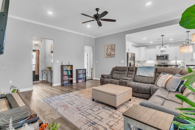 living room featuring light wood finished floors, baseboards, a ceiling fan, and ornamental molding